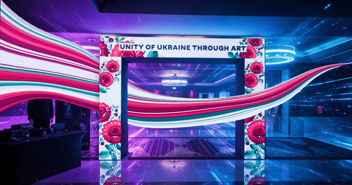 Ukrainian Petrykivka-painted archway reading "Unity of Ukraine Through Art" with a flowing red and white ribbon on LED screens
